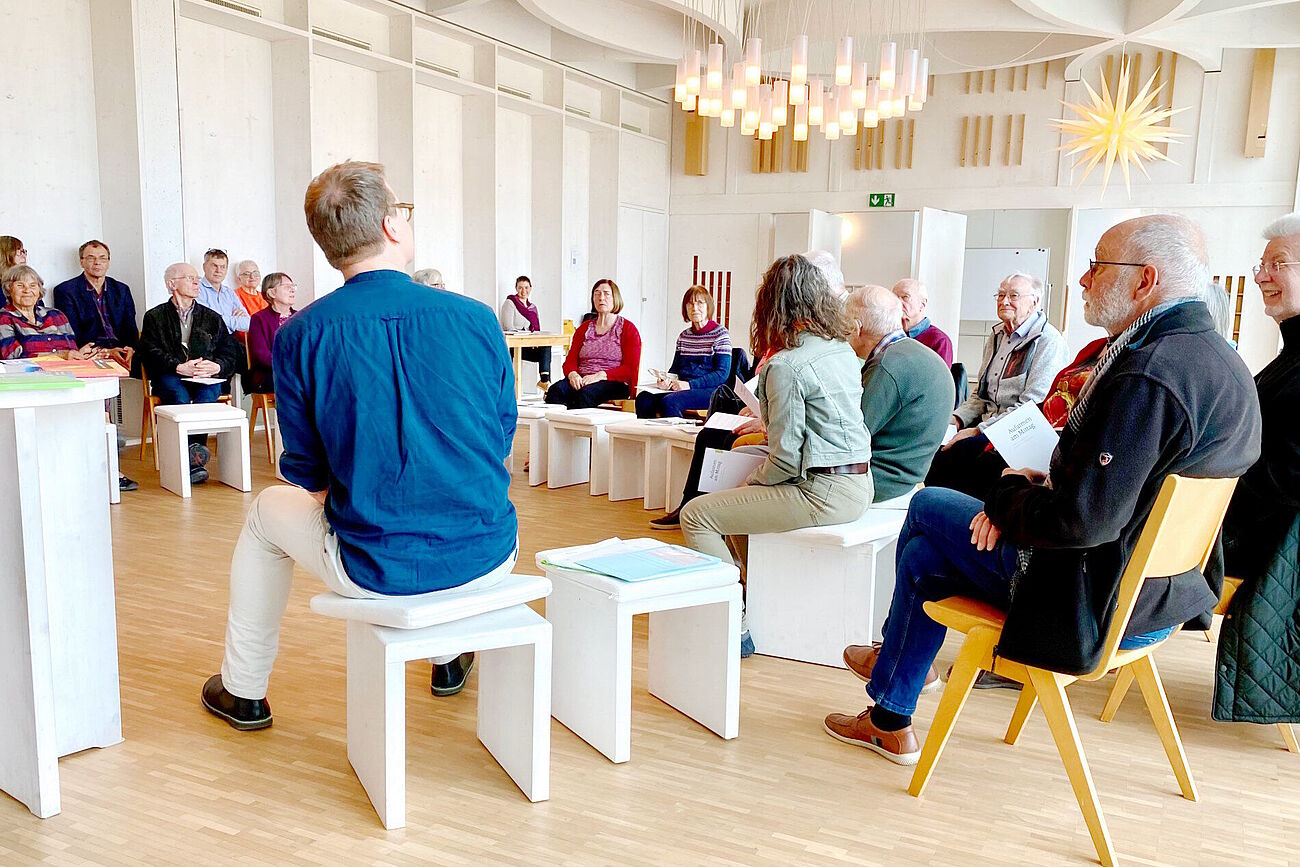 Teilnehmende im Haus der Religionen auf Stühlen und Hockern im Kreis sitzend