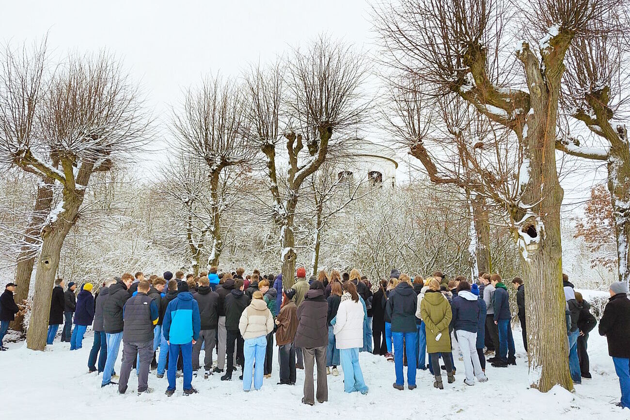 Schülerinnen und Schüler aus den Zinzendorfschulen und weitere Gäster versammelt um den Gedenkstein auf dem Gottesacker
