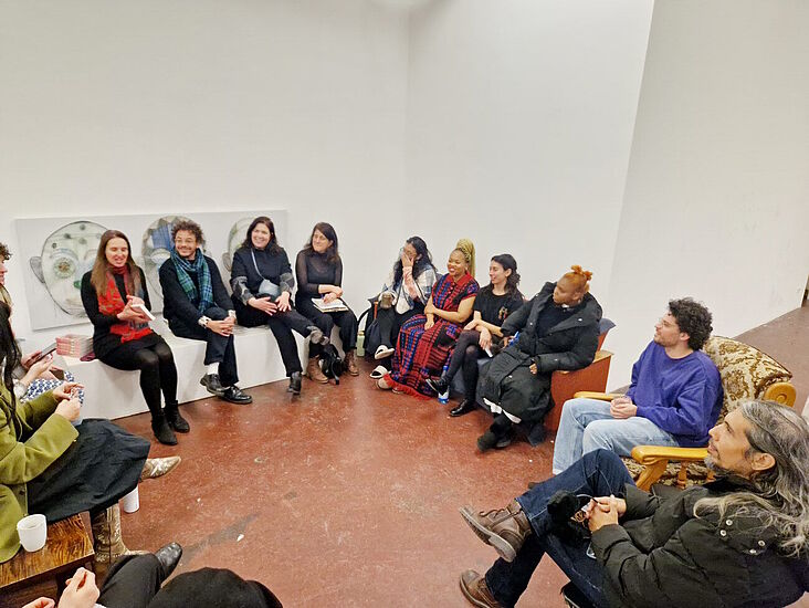 Teilnehmerinnen und Teilnehmer im Kreis sitzend bei einer Diskussionsrunde