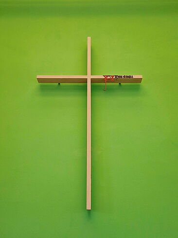 das Milíč-Kreuz an einer grünen Wand hängend