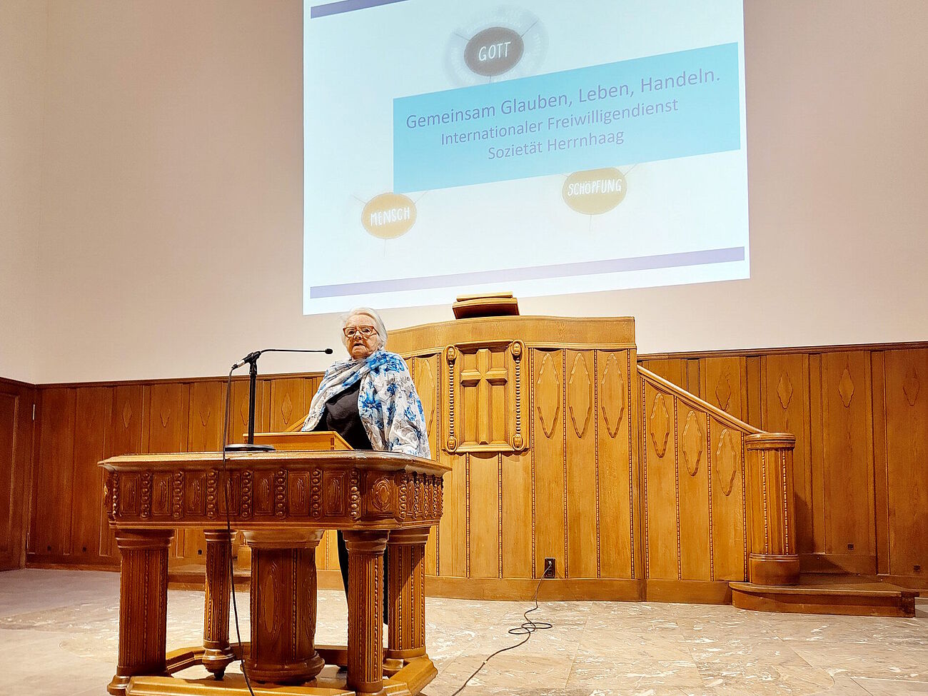 ältere Frau am Pult stehend – Vortrag in der St.-Anna-Kapelle in Zürich
