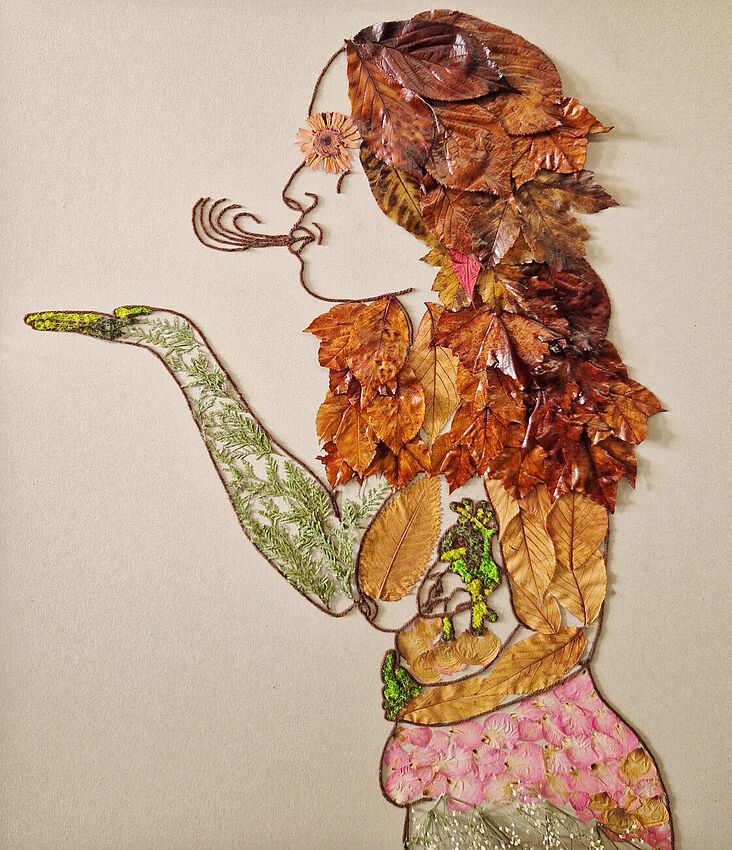Ein Bild aus Laubblättern und anderen natürlichen Materialien, welche zusammen die Dartsellung einer Frau ergeben