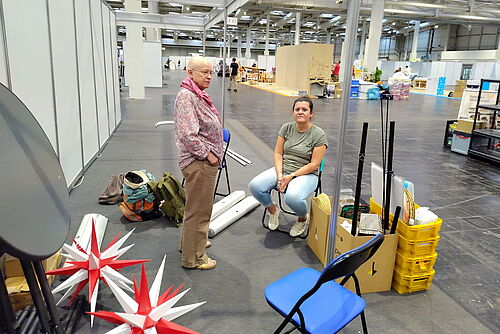 Zwei Helferinnen der Brüder-Unität warten am abgebauten Stand auf die Abholung der Materialien