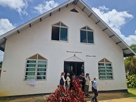 Giebelseite der Kirche; eine Gruppe von Menschen verlässt das Gebäude.