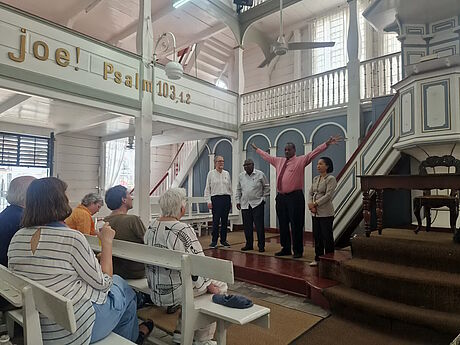 Vier Menschen im Altarraum der Kirche, einer hebt die Arme.