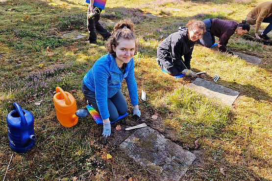 Amy Baird aus Gracehill beim Arbeitseinsatz vor einem Grabstein kniend