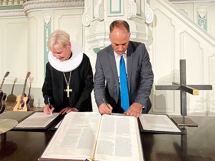 Kirsten Fehrs und Marc Brenner beim Unterzeichnen der Predigtgemeinschaft am 15. September 2024.
