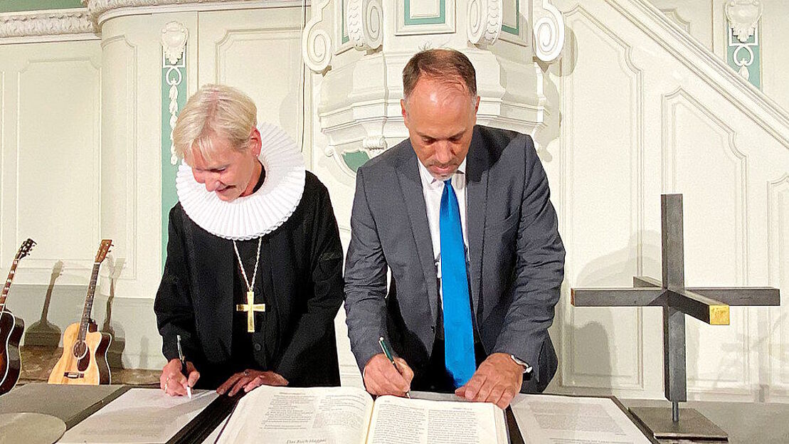 Kirsten Fehrs und Marc Brenner beim Unterzeichnen der Predigtgemeinschaft am 15. September 2024.
