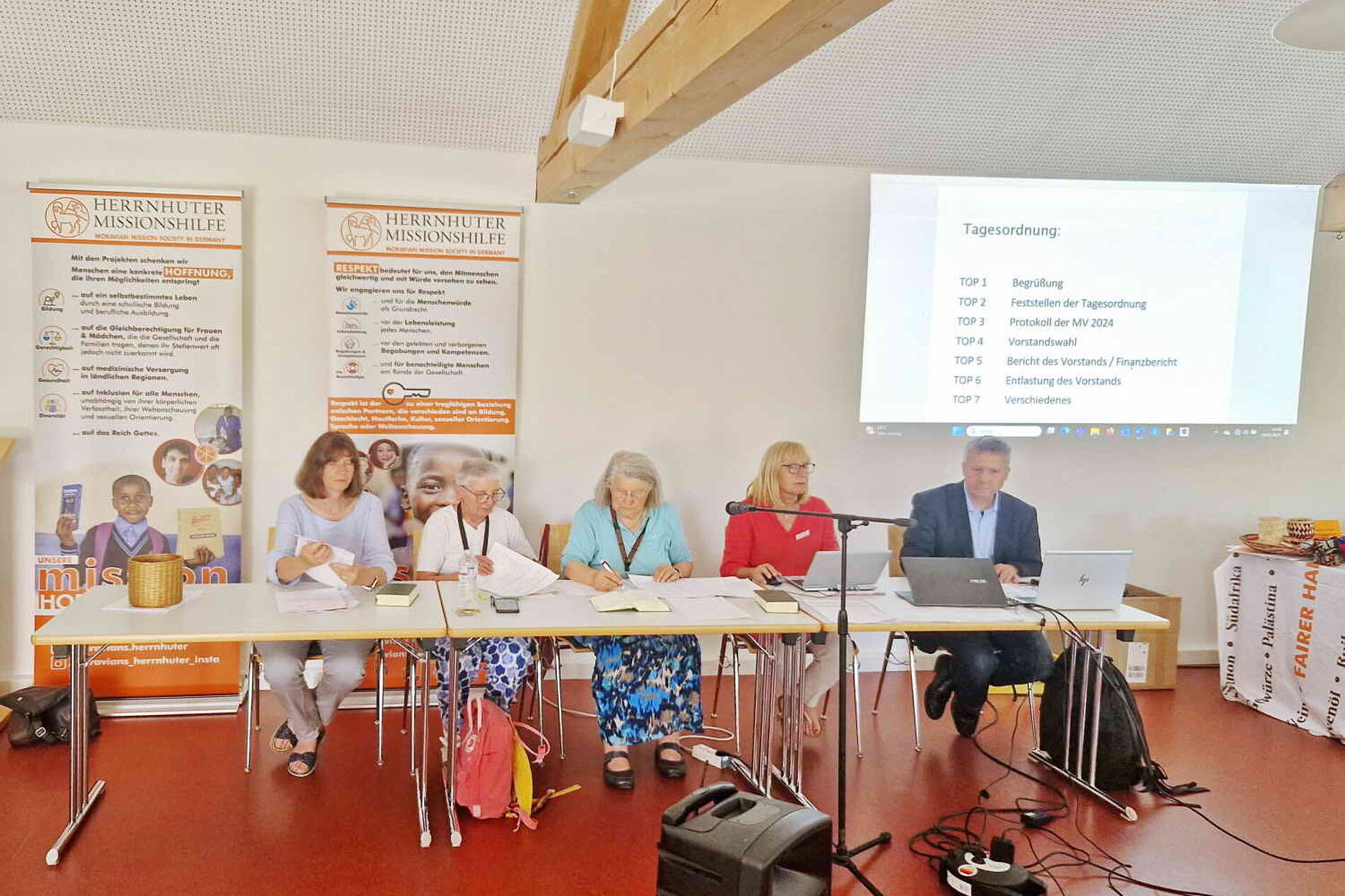 Blick auf den Vorstand, welcher die Tagesordnungspunkte vorstellt.