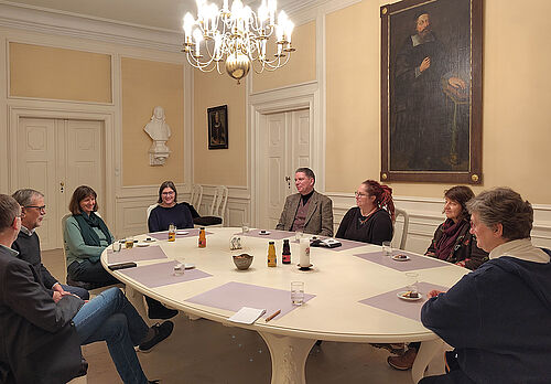 Acht Personen um einen großen Sitzungstisch - Lars-Christian Koch in der Mitte