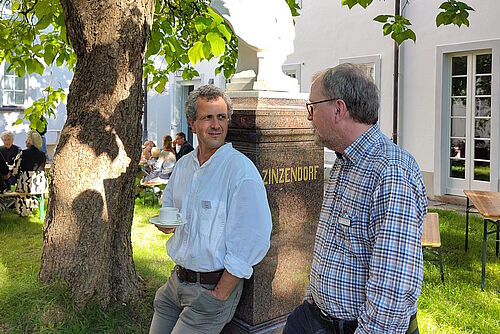 Gespräch zwischen Bernhard Mihan und Martin Theile neben der Zinzendorfbüste im Kirchgarten