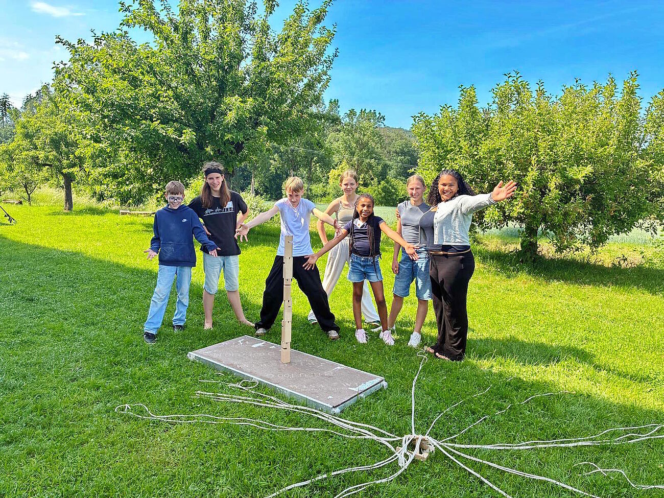 Gruppe Jugendlicher, die ein stolz ein vollendetes Stapelspiel aus Holzsteinen präsentierten