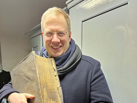 Ein Mann der sehr altes und dickes Buch in den Händen hält