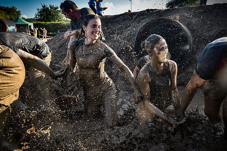 junge Menschen die versuchen, sich durch eine Schlammlache zu arbeiten