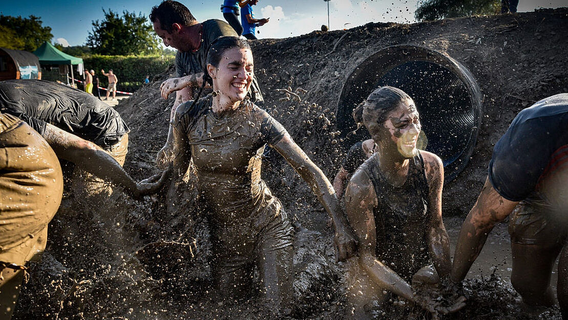junge Menschen die versuchen, sich durch eine Schlammlache zu arbeiten