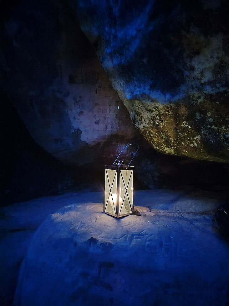 Eine Kerze scheint nachts in einer kleinen Steinhöhle
