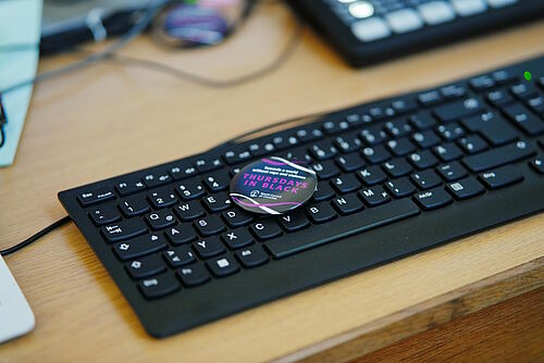 Ein Anstecker mit der Aufschrift "Thursdays in Black" liegt auf einer Tastatur