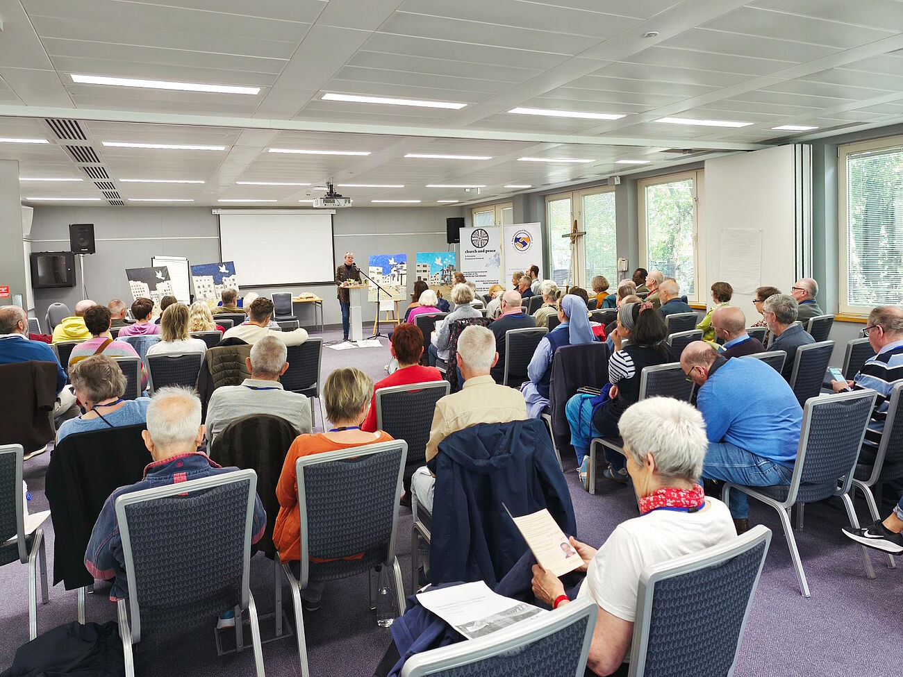sitzende Menschen von hinten fotografiert; Blick in den Konferenzraum