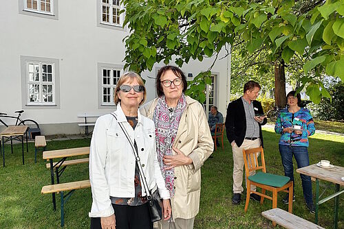 Zwei Frauen nebeneinander im Kirchgarten stehend