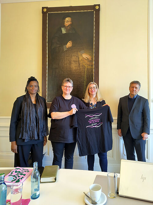 Vier schwarzgekleidete Personen vor einem Porträt von Johann Amos Comenius