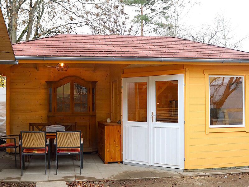 Die fertig aufgebaute gelbe Hütte mit überdachter Terrasse.