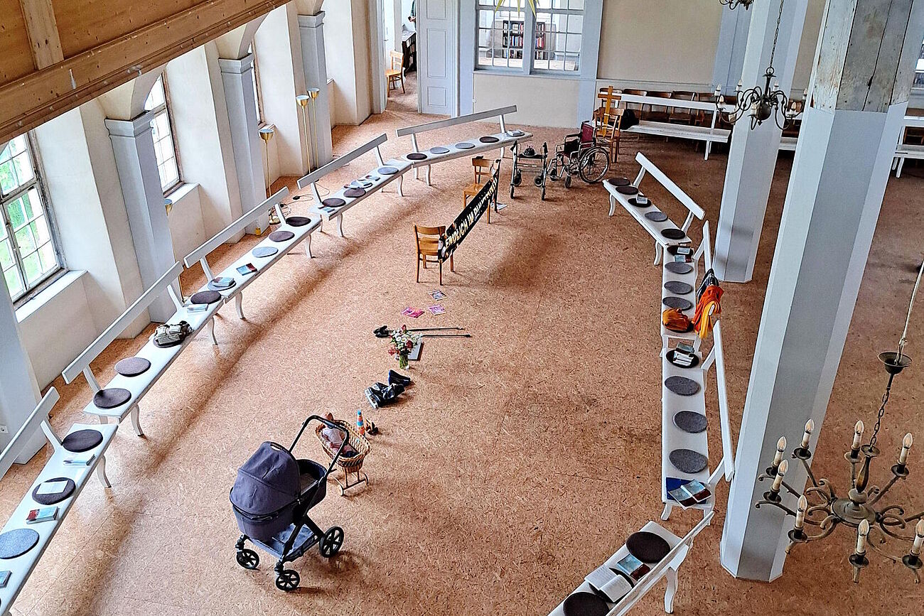 Im Saal der Lichtenburg in einer Reihe aufgestellte Gegenstände vom Kinderwagen bis zum Rollstuhl
