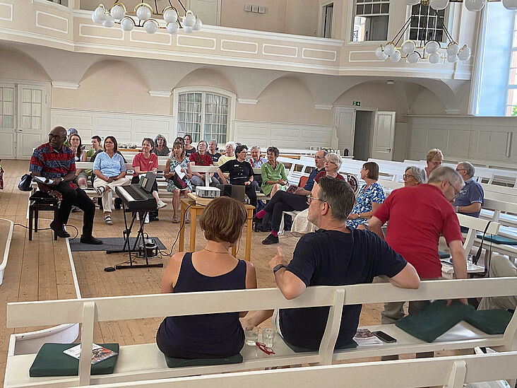 Alle Teilnehmenden sitzen im Halbkreis auf den Kirchenbänken