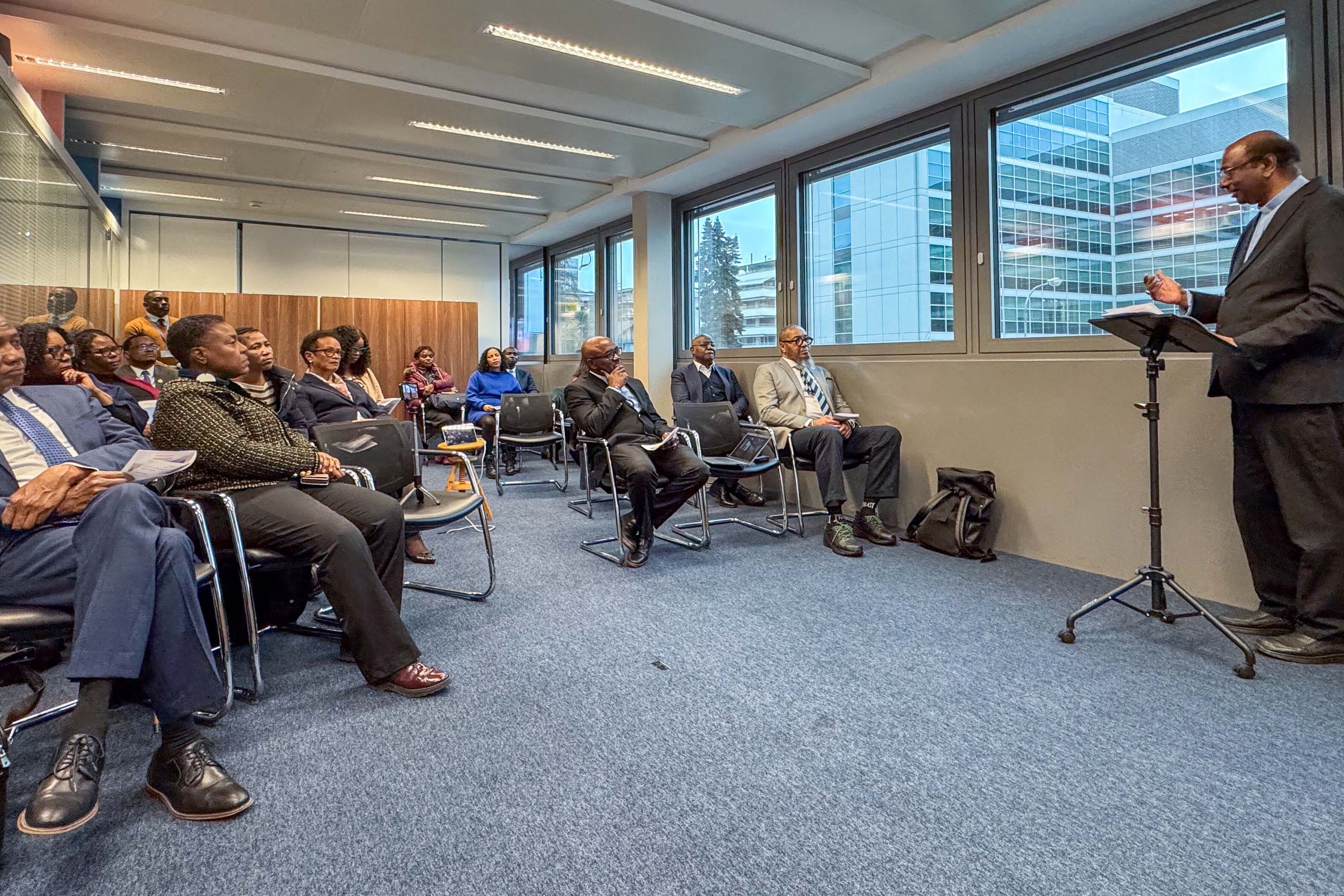 Jerry Pillay am Rednerpult, daneben etwa 20 Zuhörende