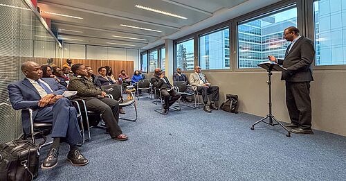 Jerry Pillay am Rednerpult, daneben etwa 20 Zuhörende