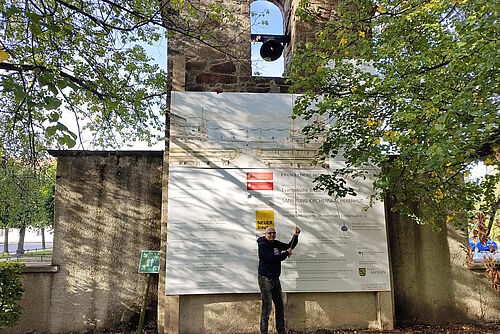 Mann läutet die historische Glocke im Kirchgarten