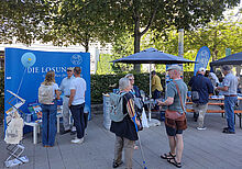 Etwa zehn Menschen im Gespräch am Straßenstand der Losungen