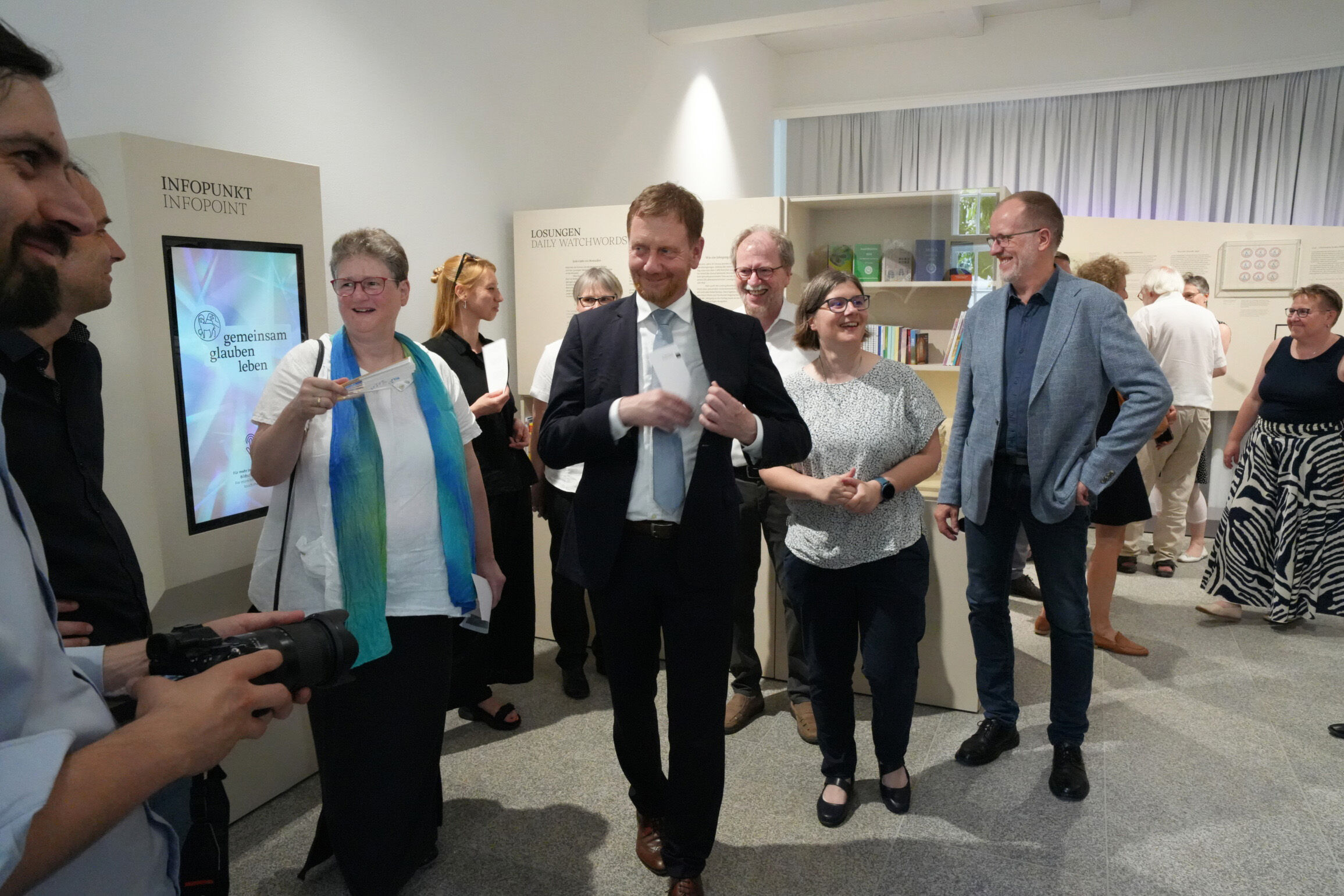 Erdmute D. Frank, Mitglied der Kirchenleitung, und Michael Kretschmer, Ministerpräsident von Sachsen laufen durch die Ausstellung