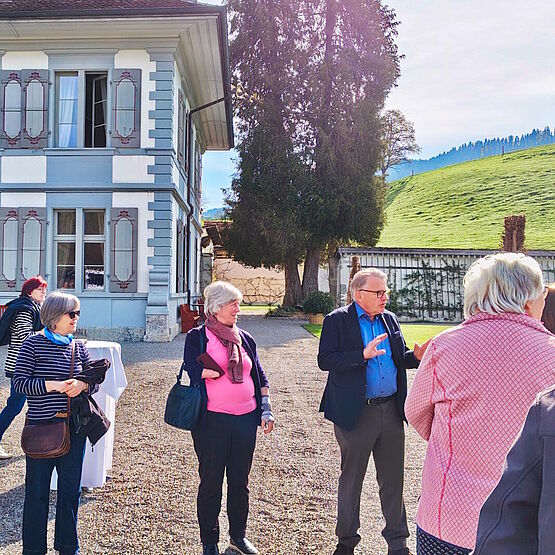 Teilnehmende der Reise im Gespräch mit Sigmund von Wattenwyl vor dem Schloß stehend