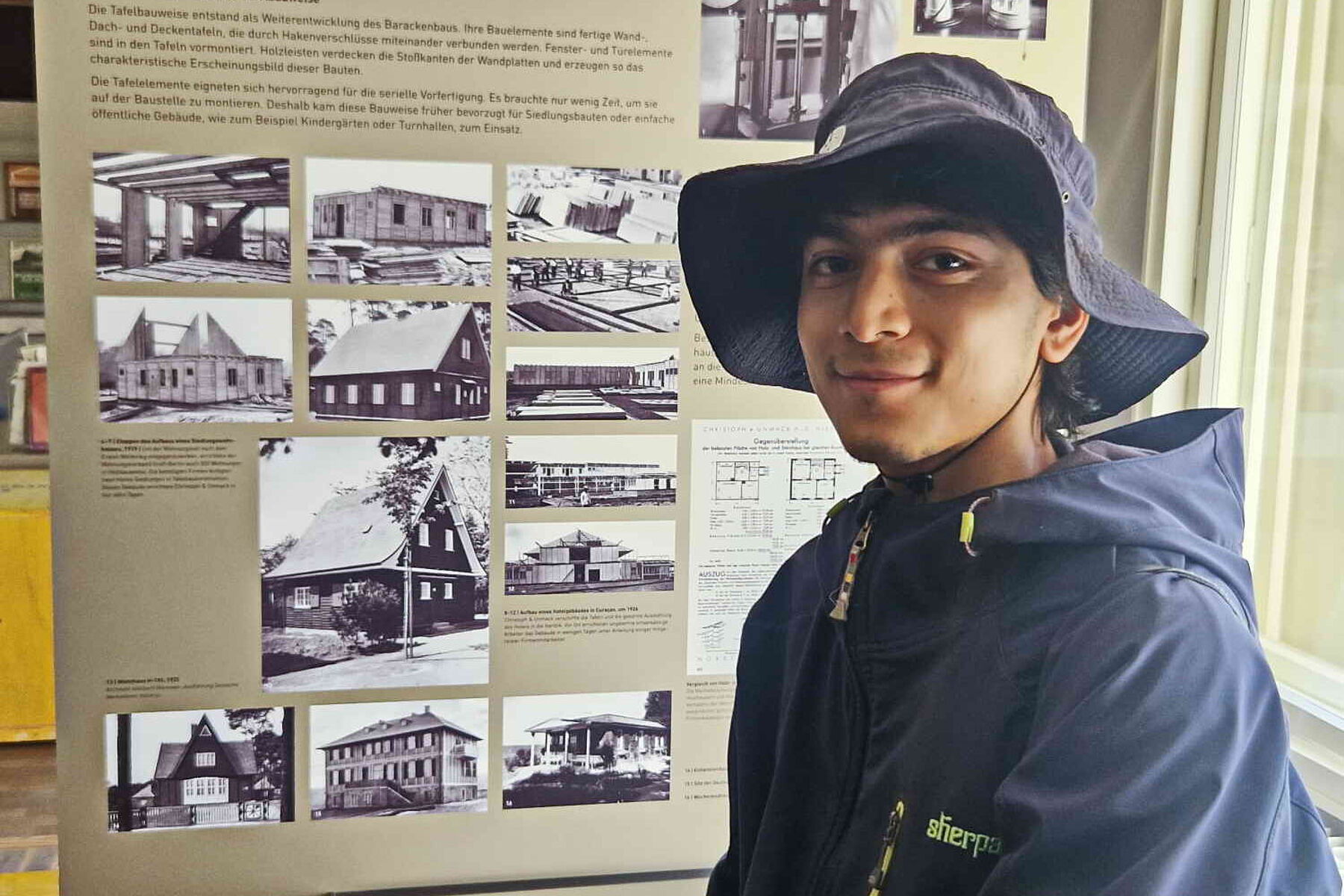 Sumin Bajracharya (Nepal) vor historischen Fotos der Holzbaukultur