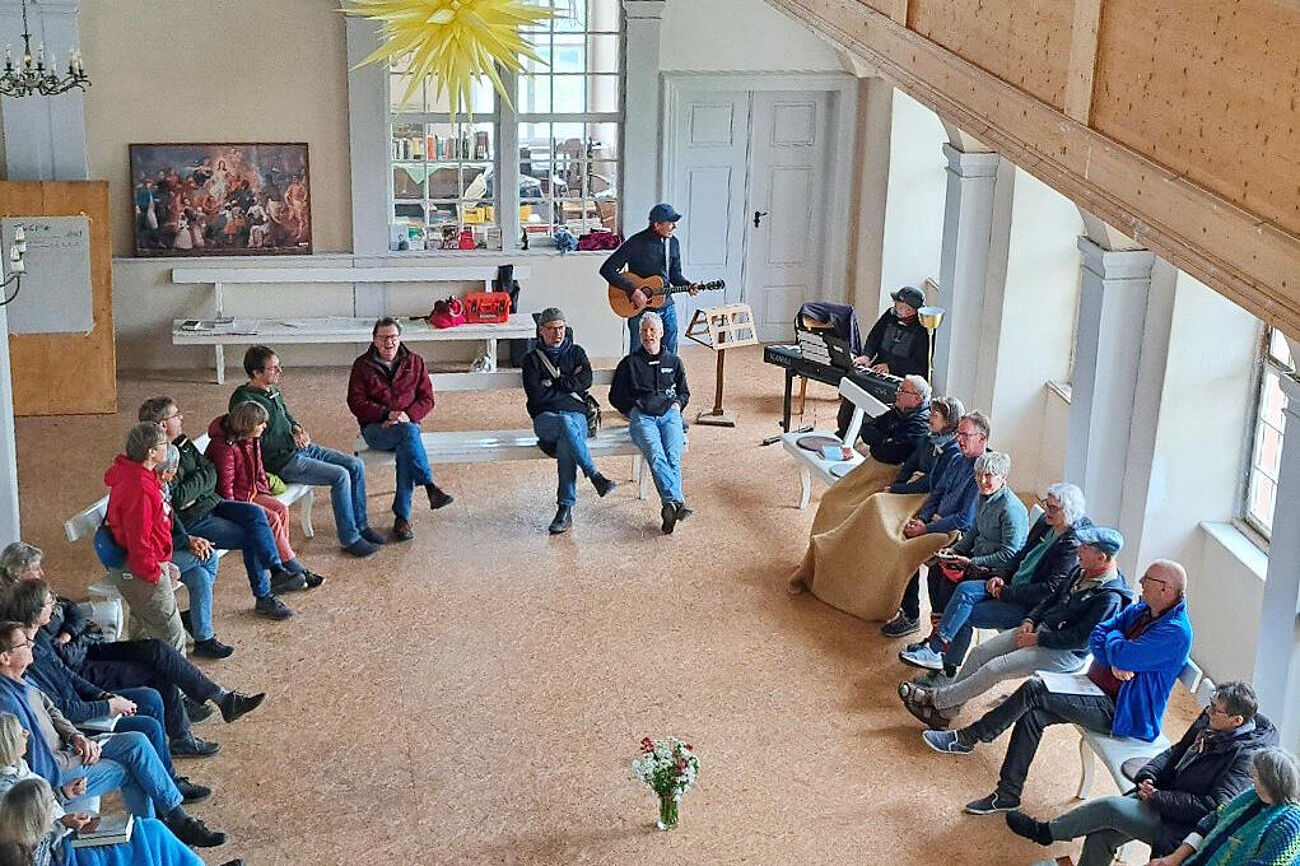 Teilnehmende im Saal der Lichtenburg im Kreis sitzend und singend
