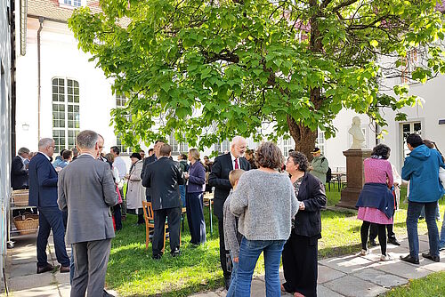 Viele Menschen im Kirchgarten kaffeetrinkend und sich unterhaltend