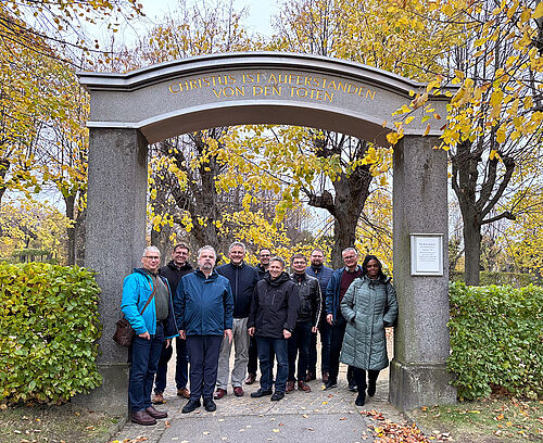 Die Mitglieder der Kirchenleitungen stehen unter dem Eingangsportal zum Herrnhuter Gottesacker