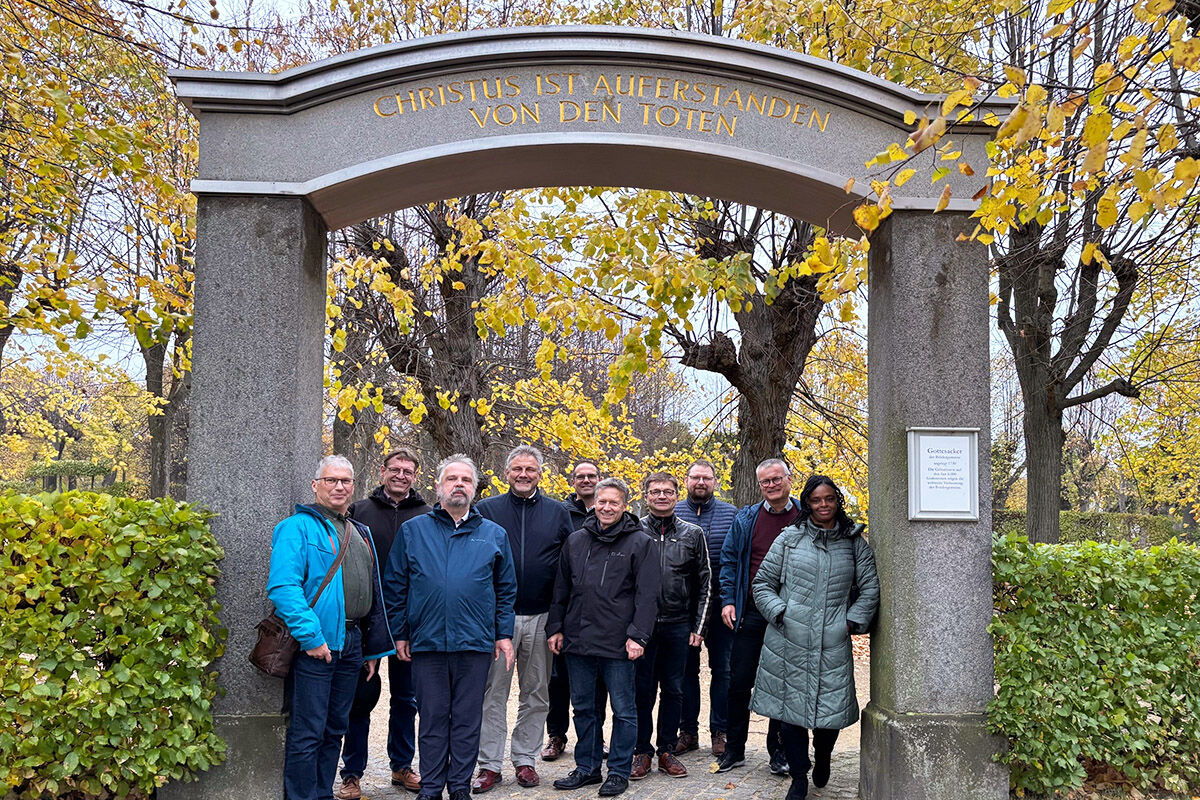Die Mitglieder der Kirchenleitungen stehen unter dem Eingangsportal zum Herrnhuter Gottesacker