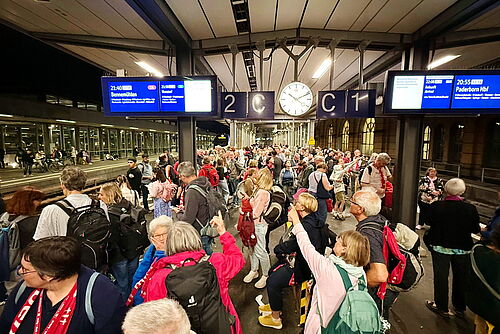 viele Menschen warten am Bahnsteig auf öffentliche Verkehrsmittel