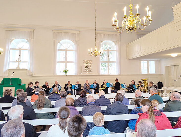 Der Bläserchor sitzt in einem Halbkreis vor der Gemeinde