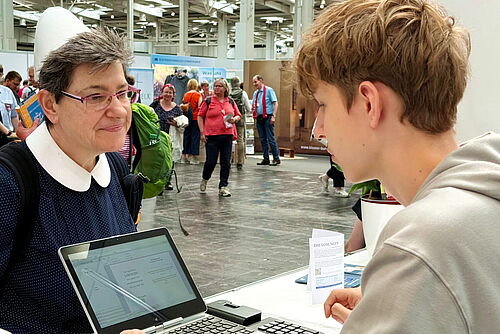 Interesse an der persönlichen Losung: Frau steht am Stand der Brüder-Unität und lässt sich eine Wunsch-Losung ausdrucken