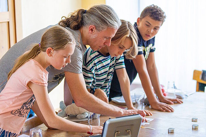 Gruppenleiter mit Kindern beim Escape-Room-Spiel