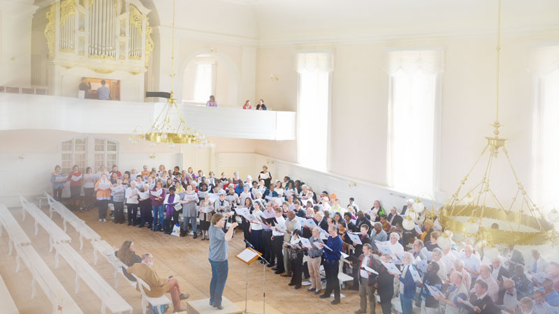 Blick in einen brüderische Kirchensaal mit vielen Sängerinnen und Sängern